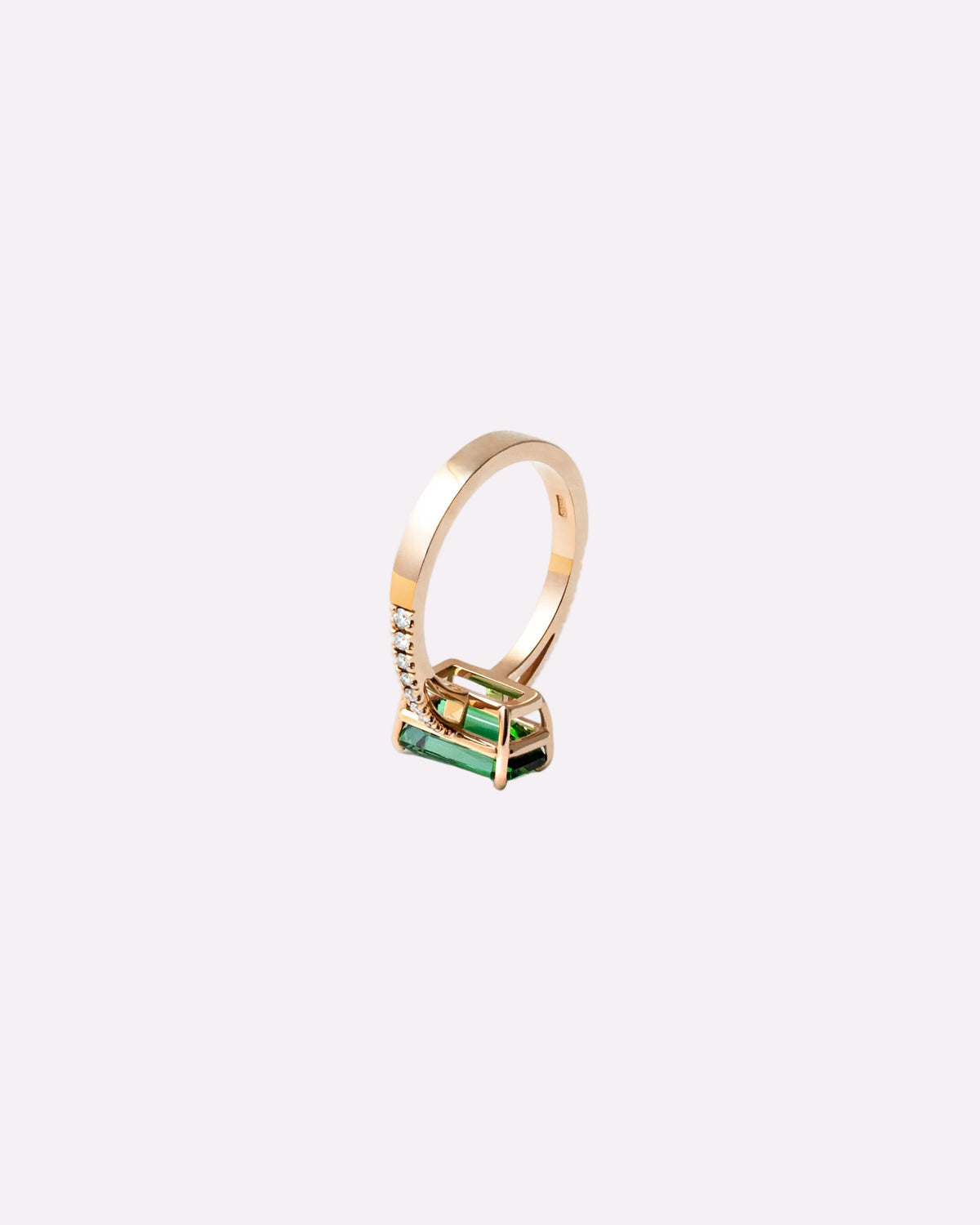 A gold ring with a geometric cage setting holding a rectangular green emerald-cut stone, shown on a clean white background.